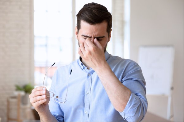 Man demonstrating dry eye symptoms including eye rubbing and discomfort from prolonged screen time and eye strain