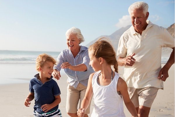 Active senior couple running with grandchildren on the beach, enjoying clear vision after cataract surgery