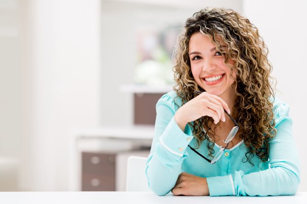 Happy young woman smiling with glasses in hand, representing visual clarity after keratoconus eye surgery
